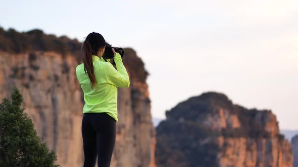 Young woman photographing mountains on camera