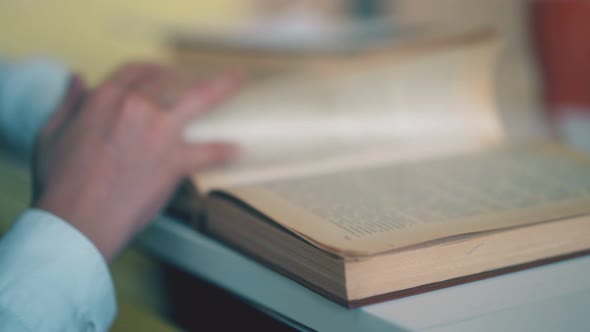 Schoolkid Turns Yellow Pages of Textbook at Table Close View