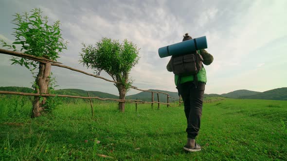 A Tourist with a Backpack Walks Along the Pathin the Background of the Mountain