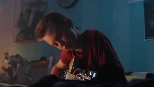 Teenager Playing Guitar in Evening