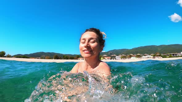 Smiling woman is frolicking in the water of the Aegean sea