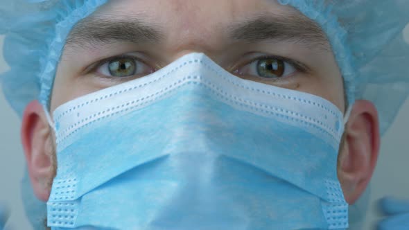 Male doctor puts on protective medical face mask before surgical treatment.
