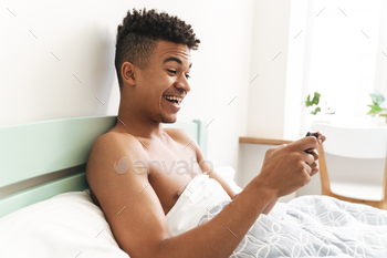 Guy in the morning play games by mobile phone in bed.
