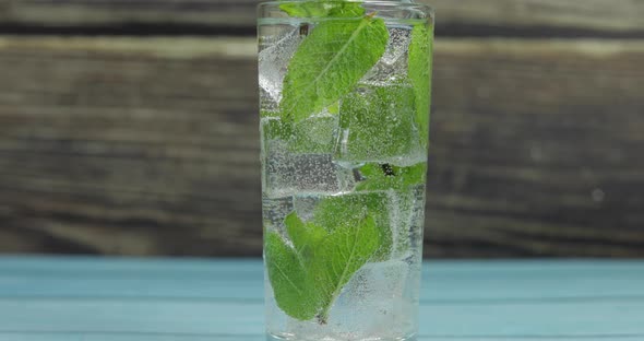 Clear Water in Glass with Green Mint Leaves and Ice Cubes