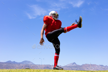 layer wearing a team uniform, training at a sports field, with one leg raised after kicking a football