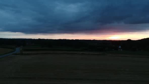 Storm clouds and golden sunset over evening agriculture fields, aerial view