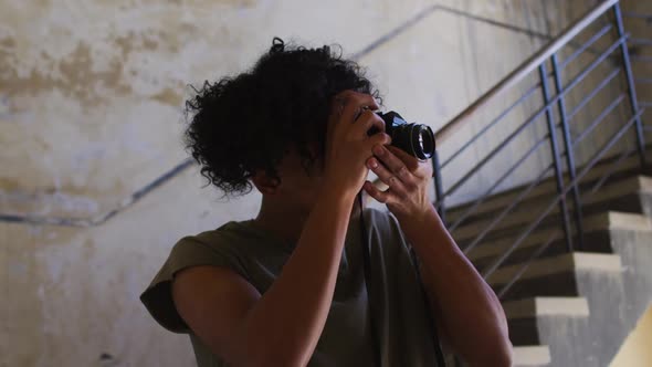 African american man taking pictures with digital camera while standing near stairs