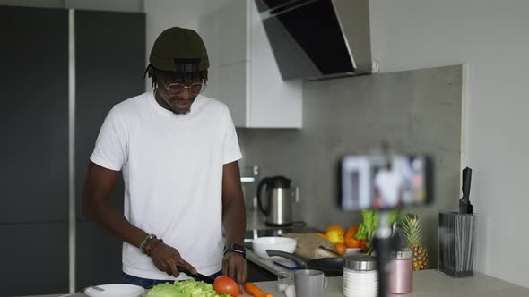 African Man Standing in Kitchen Records on Cellphone New Food Videoblog