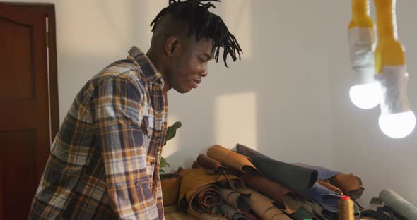 African american craftsman working at leather workshop and smiling to camera