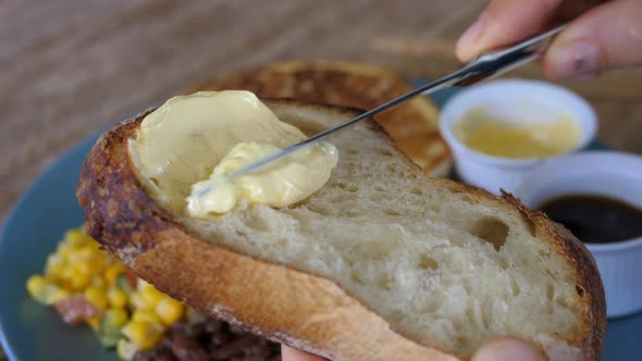 Closeup of Person Spreading Butter on Slice of Bread on Breakfast