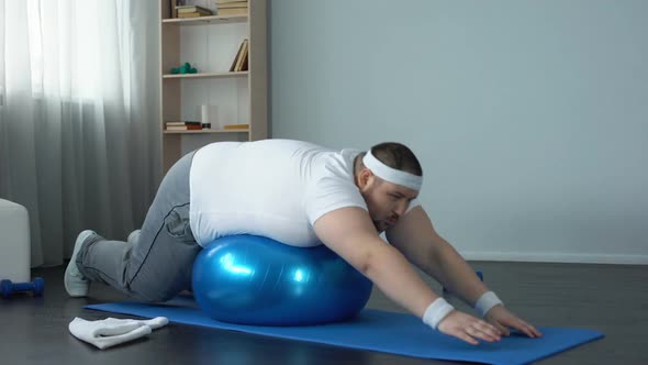 Plump Male Doing Static Exercise Effort on Fitness Ball, Desire to Lose Weight
