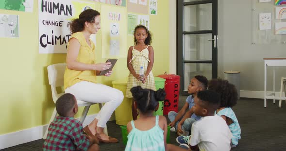 Video of happy caucasian female teacher and class of diverse pupils studying ecology in classroom