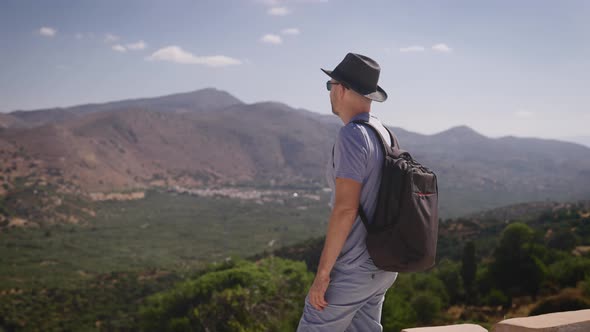 Happy Tourist with a Backpack Enjoying a Beautiful View of the Valley and Mountains