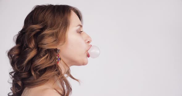 Pretty Girl with Messy Hair Blowing Chewing Gum on Yellow Background