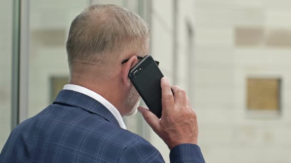 Businessman Talking on the Phone Outside of a Modern Office Building