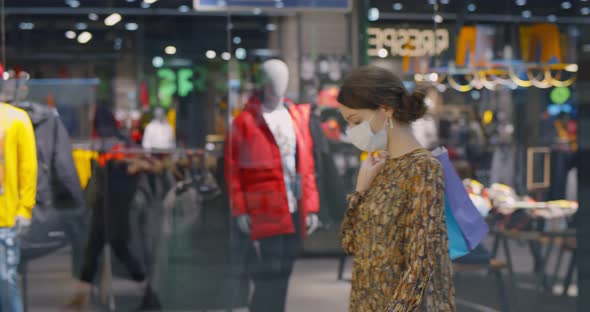 Young Woman in Protective Mask Looking at Shop Windows in Shopping Mall