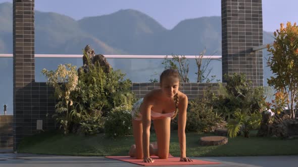 Lady Stands on Knees in Yoga Pose on Roof Terrace