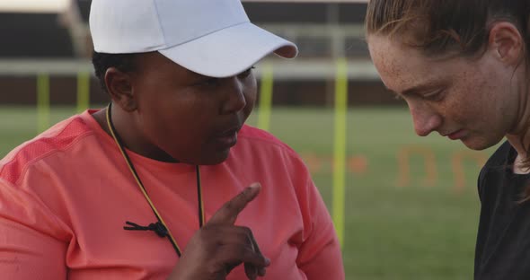 Young adult female rugby player and coach at training