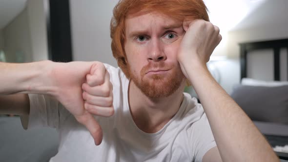 Thumbs Down by Casually Sitting Redhead Man