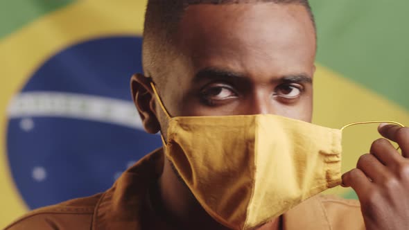 Young Black Man Removing Face Mask and Posing on Brazilian Flag