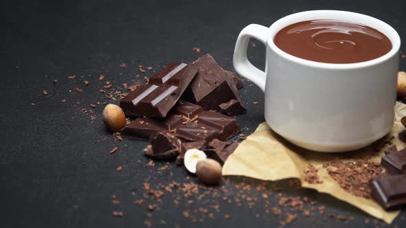 Cup of Hot Chocolate and Pieces of Chocolate on Dark Concrete Background
