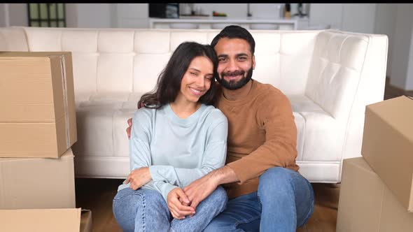 Happy Indian Newlyweds Moved in New Apartment Sitting on the Floor Among Cardboard Boxes