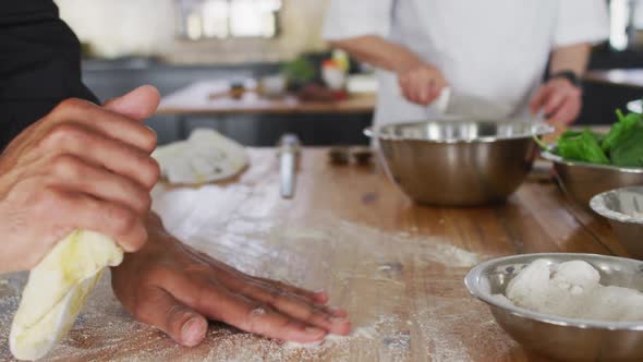 Mixed race male chef kneading dough on a kitchen table