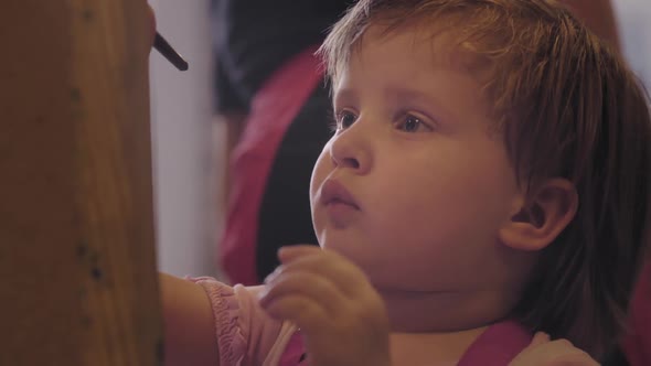 The Little Girl Concentrated on Drawing Canvas.