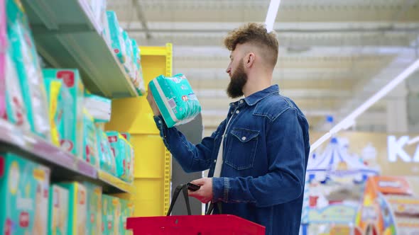 Young Father is Buying Diapers for New Born Baby in Supermarket