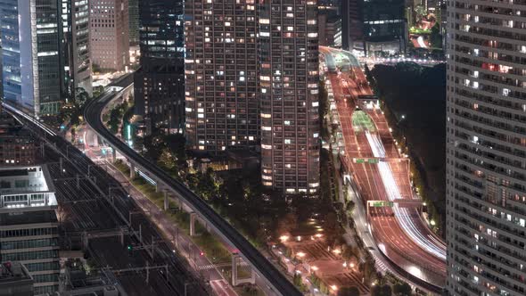 Traffic And Train Travelling In Tokyo City At Night Passing By Condominiums And Hotel From Seaside T