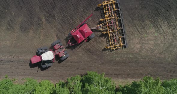 Aerial View of the Tractor Works in the Field Sows and Plows the Soil at the Same Time