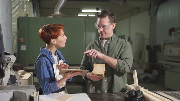 Two Carpenters Working with Equipment on Wooden Table in Carpentry Shop