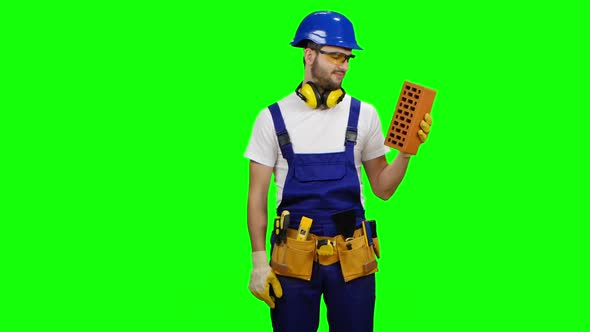 Engineer Holds a Brick in His Hand and Shows a Thumbs Up. Green Screen