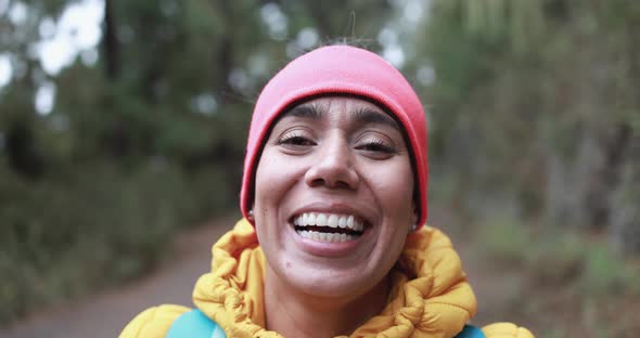 Latin woman smiling on camera during trekking day in the forest