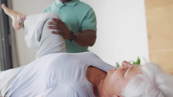 Video of african american male physiotherapist exercising with caucasian senior woman