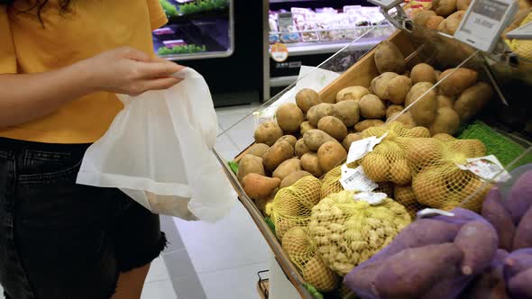 Attractive Young Woman Chooses Potatoes Shopping in the Supermarket Buys Healthy Food Potatoes in