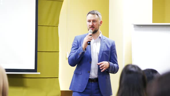 Successful manager conduct a meeting. Handsome businessman talks into a microphone