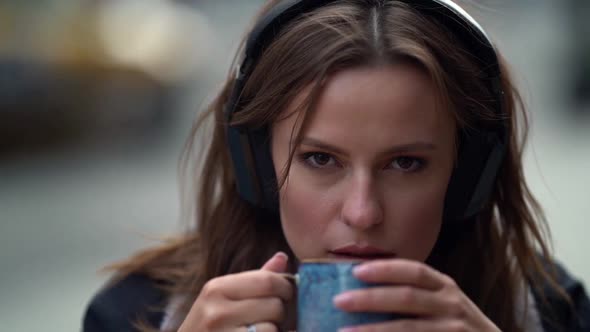 Portrait of a Sad Young Woman Listening To Music Using Headphones Outdoors. Sitting on an Autumn