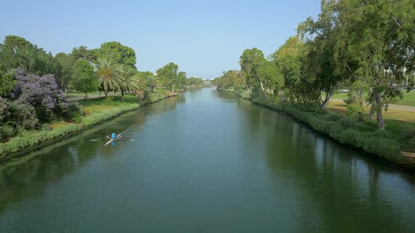 Cinematic tracking shot of Yarkon River passing Green Trees and a rowing boat