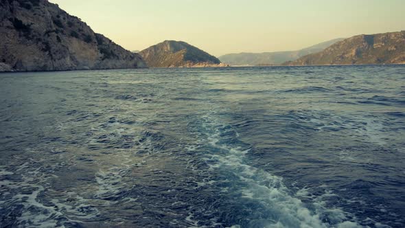 Slow Motion View Sea Wave Behind Pleasure Boat In Sunset. Sea View From Boat At Sunset. Trip Concept