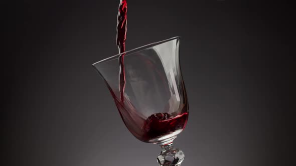 Pouring Red Wine Into Shiny Glass Over Black Background