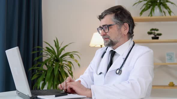 Senior Doctor Talking During Video Chat on Laptop