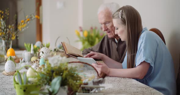 Young Woman Surfing Internet with Grandfather on Digital Tablet