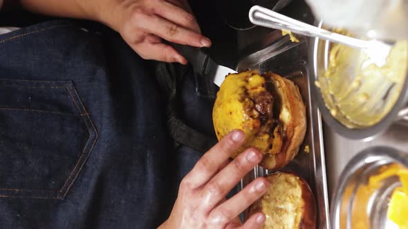 Chef Placing Burger Patty With Melted Cheese On Top On Burger Bun. close up, vertical