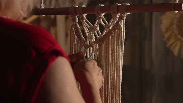 Woman Weaves Pattern Macrame on a Stick in Her Home Workshop