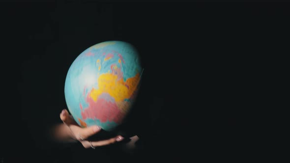 Girl's Hands Twist the Geographic Globe Around Its Axis