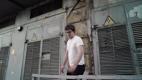 Adult Man Standing on Background of Grey Old High Voltage Doors