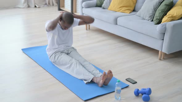 Healthy African Man Doing Stretches on Yoga Mat at Home
