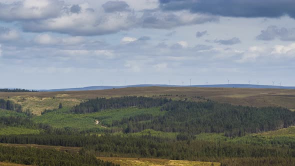 Time lapse of mixed forestry rural landscape and wind turbines on distant hills on a summer cloudy d alt