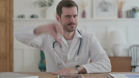 Young Doctor Showing Thumbs Down While Sitting in Clinic